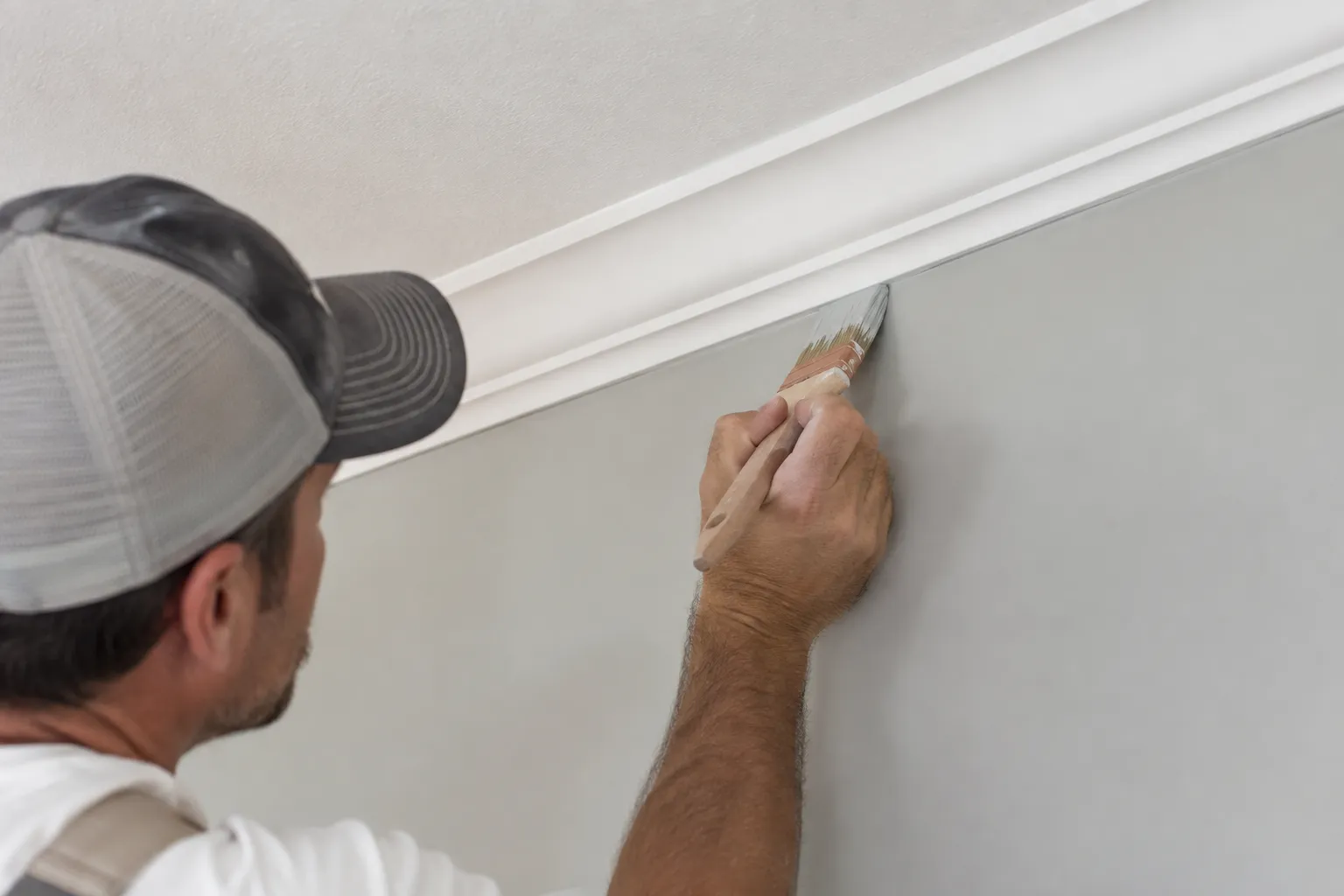 Close-up of a painter cutting in a crisp line between wall and ceiling trim
